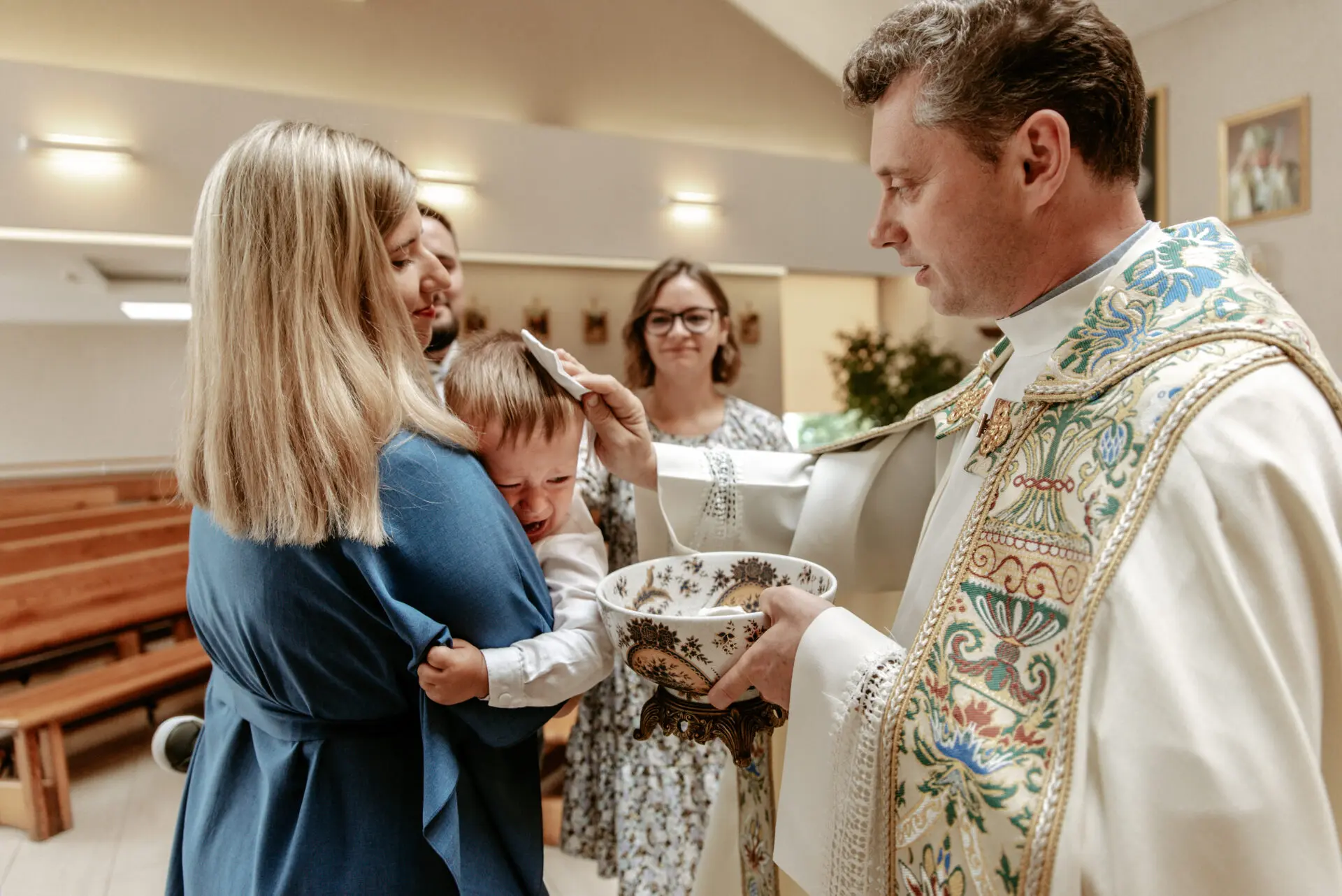 Kunigas nušluosto šventą vandenį nuo verkiančio vaiko