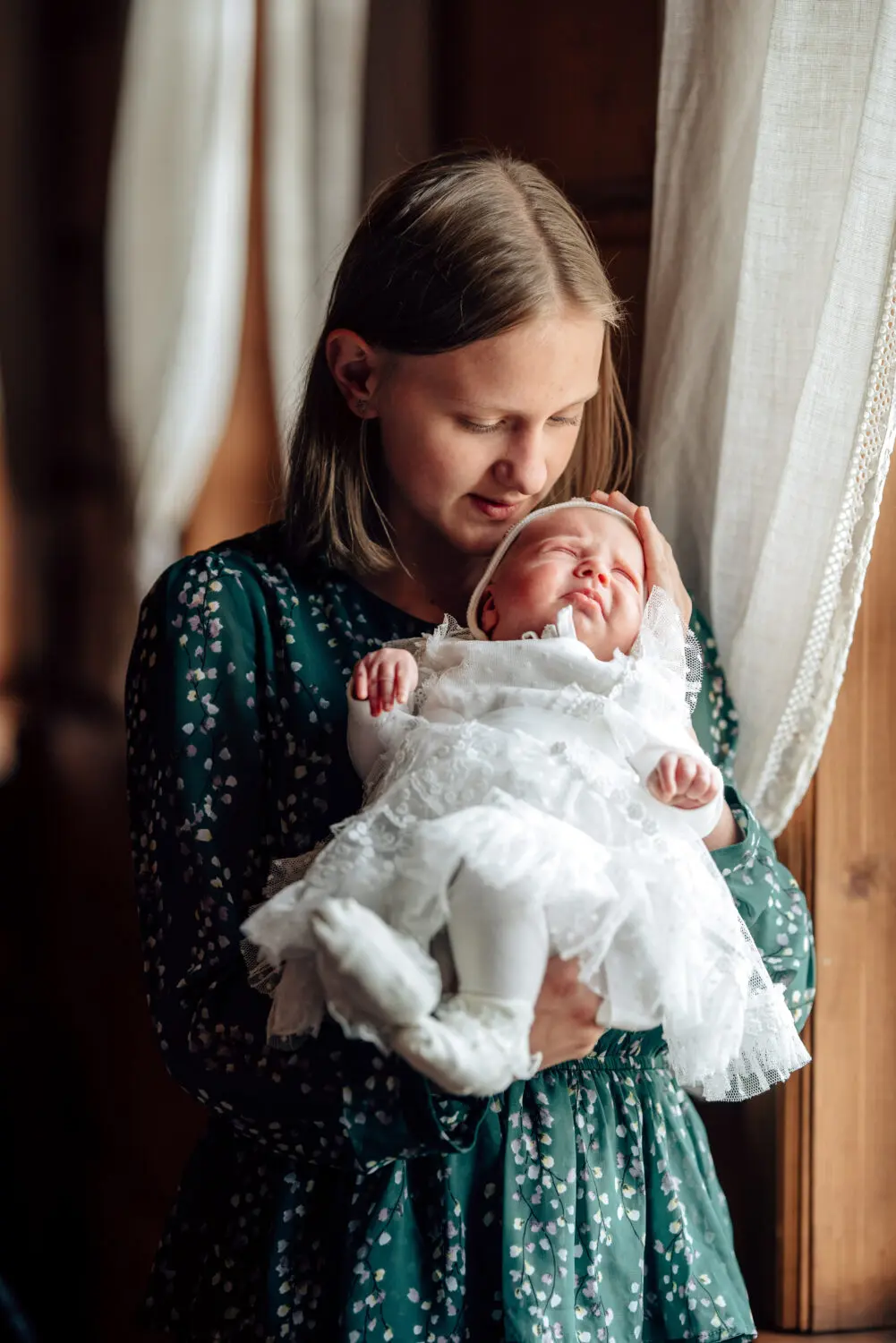 Mergaitė laiko savo pusseserę prie lango