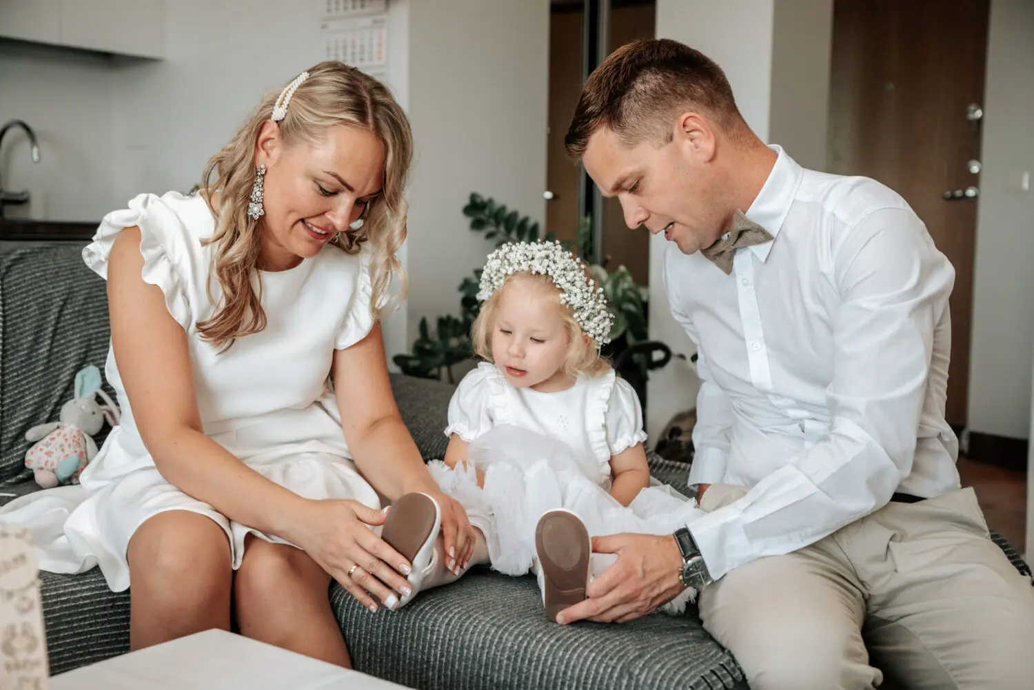 Krikštatėviai uždeda batelius jų būsimai krikšto dukrai