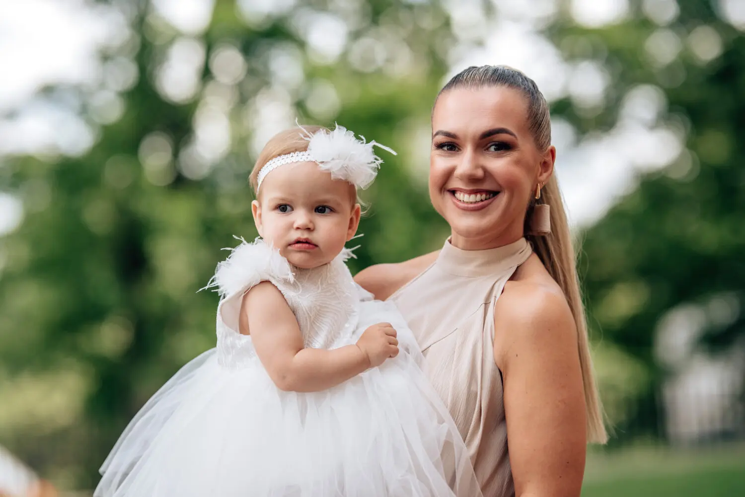 Mama laiko pakrikštytą dukrą fotografuojantis prie bažnyčios