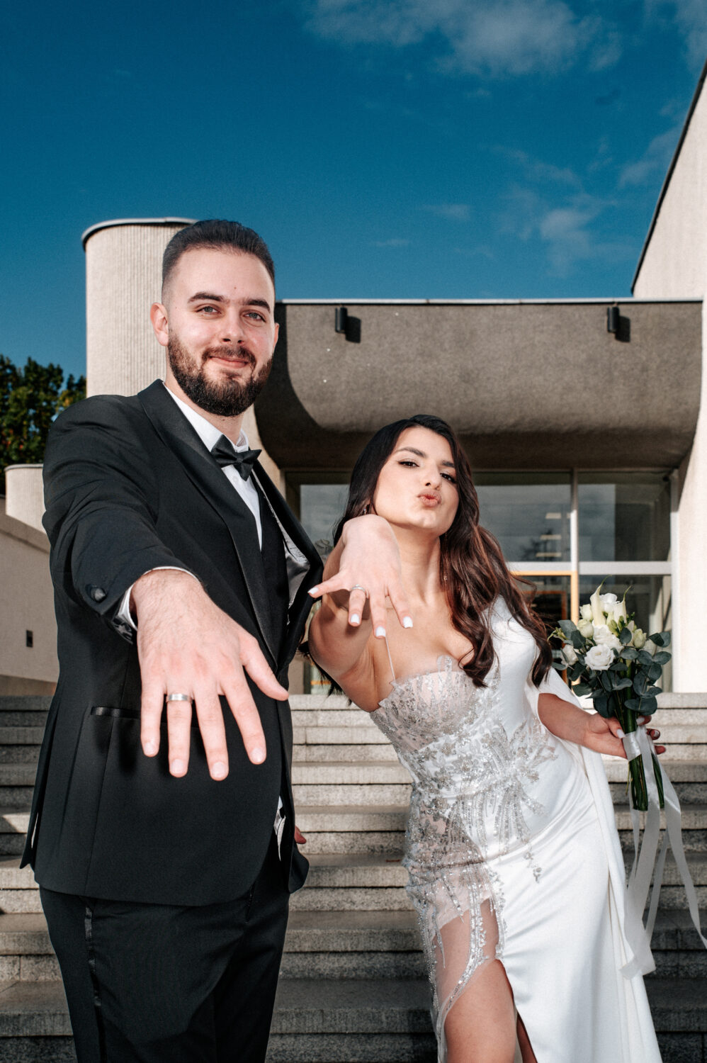 Pora už parankių eina Vilniaus senamiesčio Dominikonų gatve, žiūri vienas į kitą, fone Šv. Jonų bažnyčios varpinės bokštas