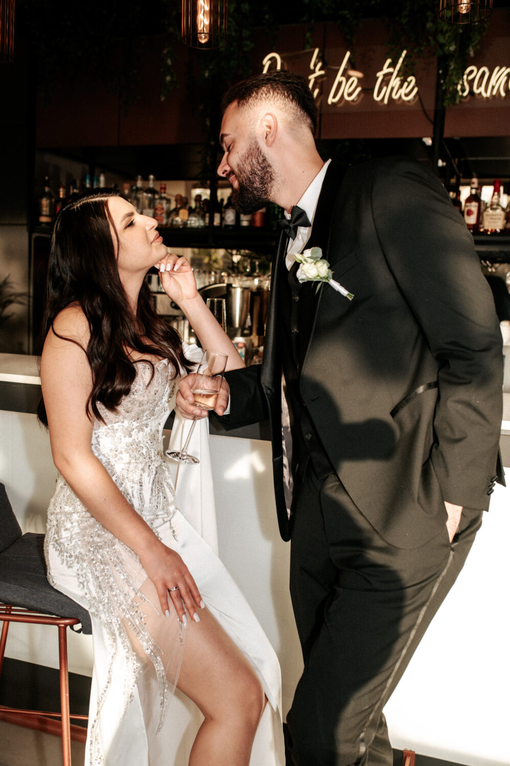 Vyras atisuka pažiūrėti į savo žmoną, jų vestuviniai drabužiai, kostiumas ir suknelė puikiai dera viens prie kito.